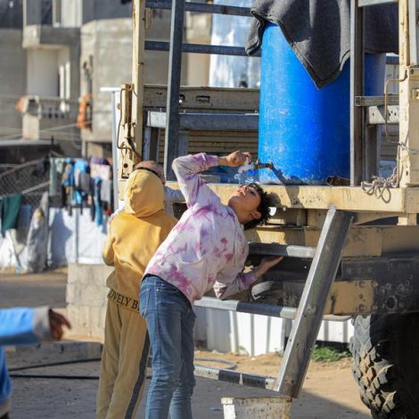 a thirsty girl dropping water in side her mouth directly in the southern Gaza Strip city of Rafah, Palestine